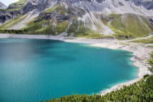 Голубая прозрачная вода возле высоких гор