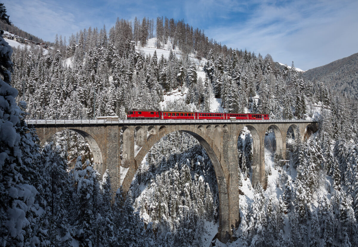 Красный поезд RhB на заснеженном виадуке