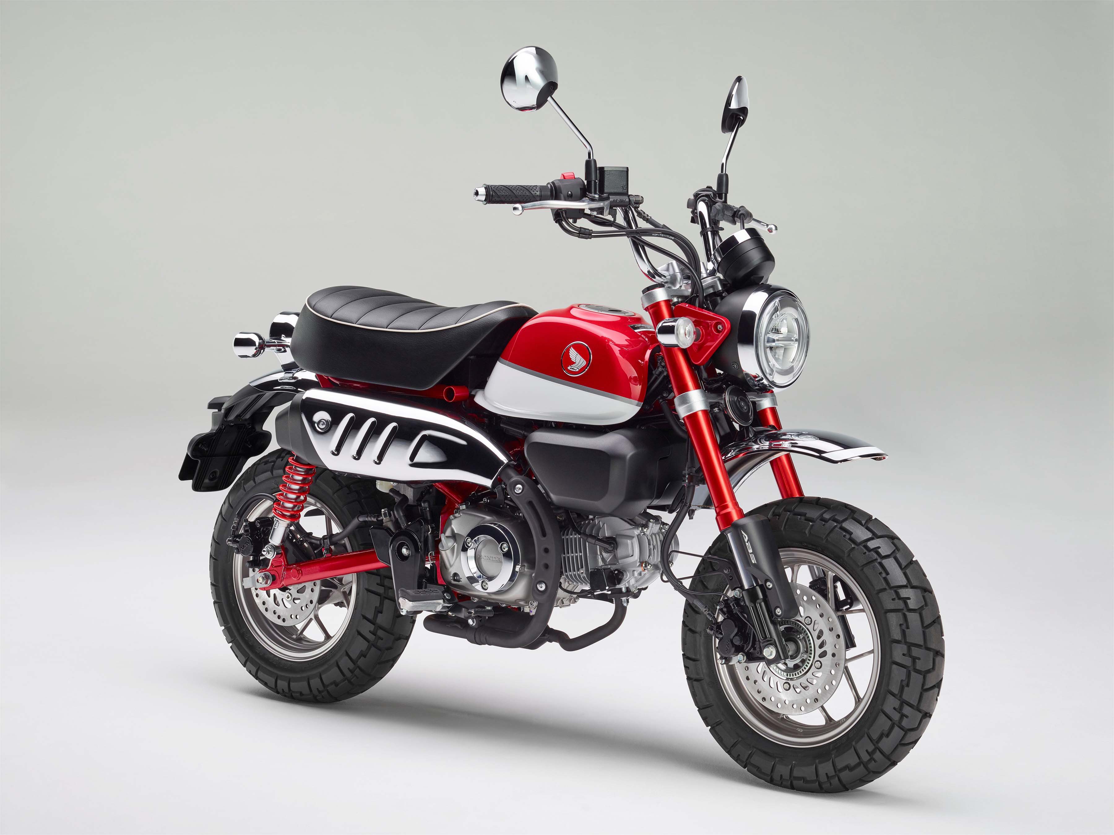 На сером фоне красный мотоцикл Honda Monkey, 2018 года