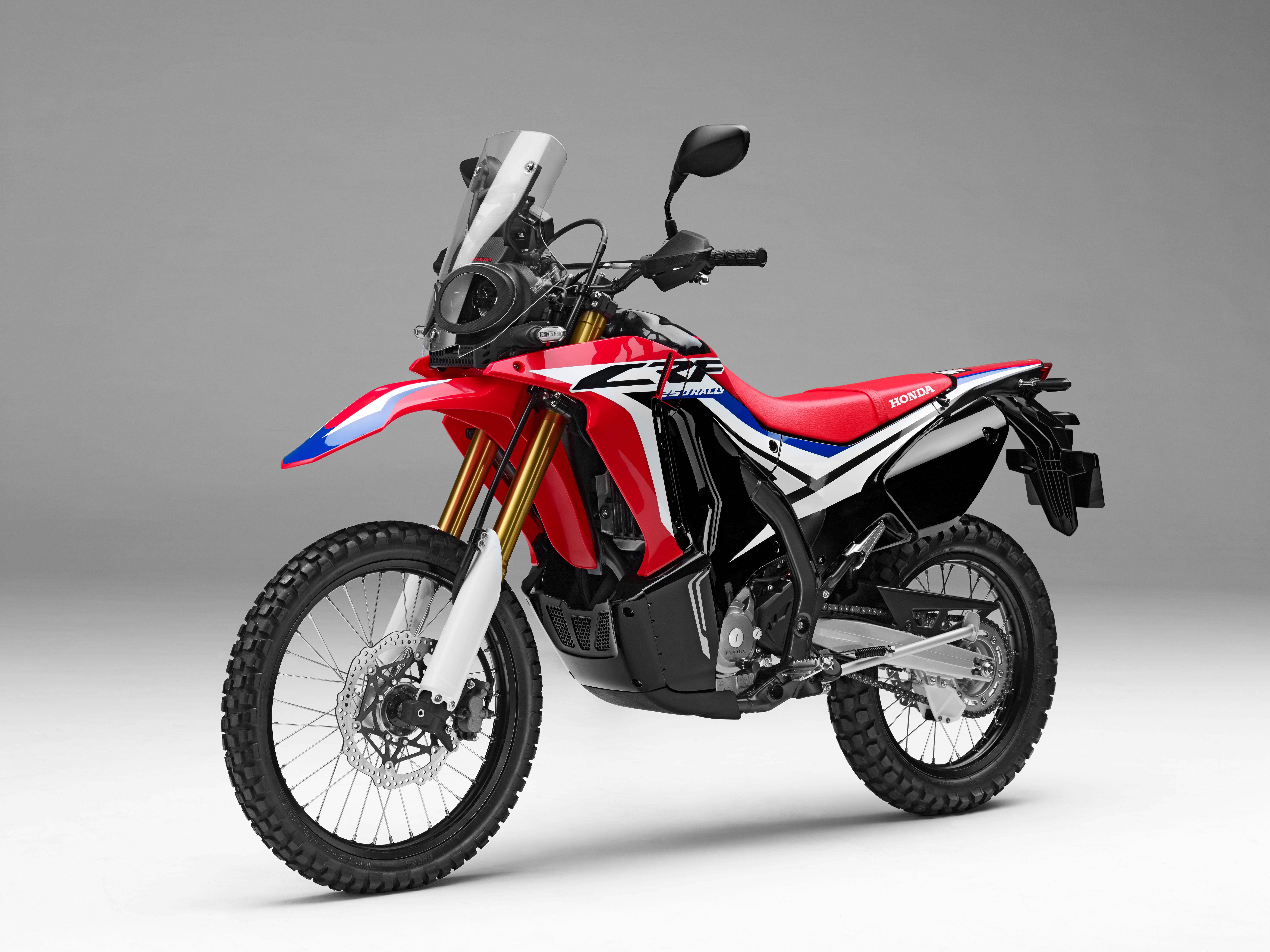 На сером фоне спортивный мотоцикл Honda crf250l Rally