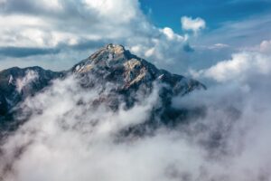 Высокая горная вершина в плотных белых облаках